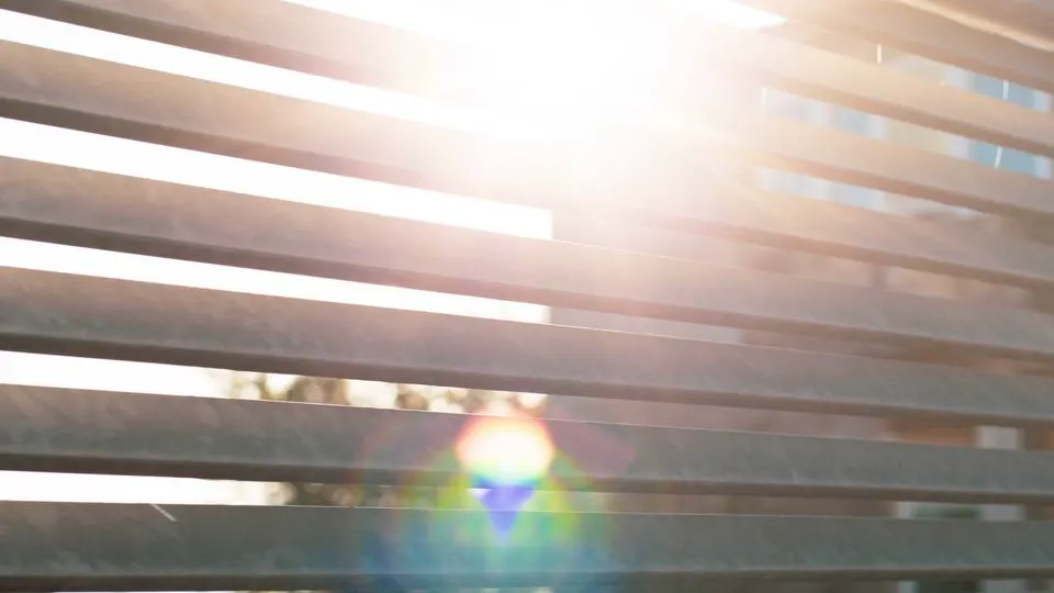 Metalne letvice ograde kroz koje prolazi sunce